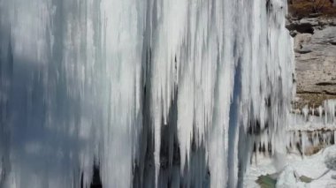 Hava Kış çağlayan beyaz köpüklü buz sarkıtları içine dondurulmuş. Kış gününde kayalık dağ kayalıklarından sarkan çarpıcı donmuş buz sarkıtları. Erken bahar güneş ışınları buzlu şelale eritme. Fantastik kış manzarası