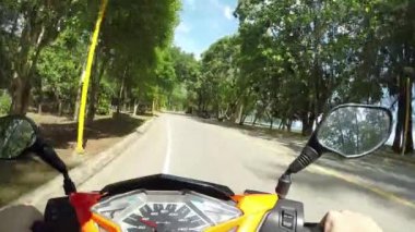 Pov: Pitoresk egzotik doğa ile serin bir turuncu ve siyah scooter Sürme. Krabi güneşli plaj yakınında açık bir yolda pastoral bir motosiklet gezisi giderek yaz tatili zevk.