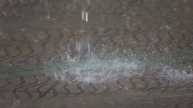 Yavaş Hareket, Yakın Çekim, Dof: Şiddetli yağış sırasında boş sokağa dev su damlacıkları çarptı. Sayısız camsı damla kahverengi ve gri kaldırım çarptı. Gökten düşen yağmurun sinematik görüntüsü.
