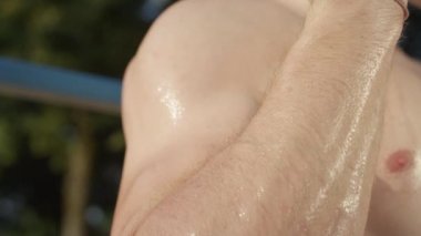 Slow Motion, Close Up, Dof, Macro: Kaslı kolları güneşli bir günde dışarıda egzersiz yaparken titreyen bilinmeyen genç adam. Tanımlanamayan yetişkin erkeğin terli kol kasları yaz güneşinde parlıyor..