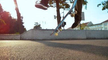 Slow Motion, Lens Flare, Close Up: Bilinmeyen kaykaycı güneşli şehirde beton kaldırımda yürürken havalı bir numara yapıyor. Kaykayın insanların ayakları altında havada uçuşunun sinematik görüntüsü.
