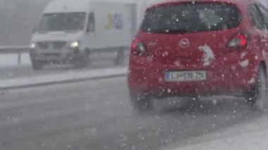 Ljubljana, Slovenya, Şubat 2017 - Şiddetli bir kar fırtınası sırasında Dof: Arabalar yol boyunca ilerlerken gökyüzünden düşen kar tanelerinin sinematik görüntüsü.