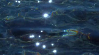 Yakın çekim: sakin kristal berrak okyanus suyunun göz kamaştırıcı yaz güneşinde parlayan görüntüsü. Denizin sakin yüzeyi parlıyor ve güneş ışınlarını yansıtıyor. Işıldayan suyun serinliğini kapat.