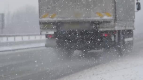 慢动作 卡车和货车沿着危险的雪地公路行驶 恶劣的天气条件使高速公路上的大雪纷飞 交通减慢 — 图库视频影像