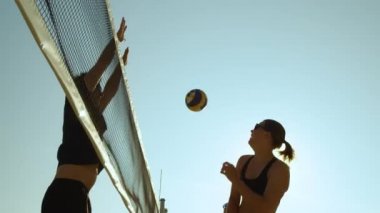 Slow Motion, Close Up, Low Angle, Lens Flare: Uzun adam atletik bayan voleybolcu tarafından çivilenen topu engelliyor. Formda kadınlar ve erkekler yaz tatilinde güneşin altında voleybol oynuyorlar..