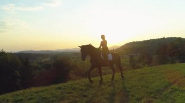 Anteni, Lens Flare: Uçan boyunca genç kadın güneş doğarken onu güzel kahverengi at binme. Pastoral kırsal aracılığıyla onu atlı paça mutlu beyaz kız. Slovenya pitoresk günbatımı.