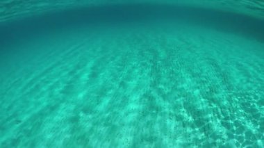 Slow Motion, Half Underwater: Kumlu okyanus tabanının ve kristal berrak Akdeniz 'deki manzaralı adanın sinematik görüntüsü. İtalya 'da güneşli bir günde, cennet manzarasının yarısı nefes kesici..