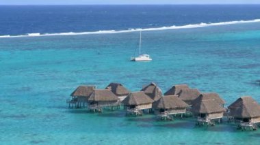Bir lüks otel Resort rüzgarlı yaz gününde nefes kesen turkuaz denizde küçük ahşap bungalov. Üfleme geçmiş bir beyaz Yelkenli ve oceanfront villalar overwater güçlü rüzgarlar. Tatil konaklama.