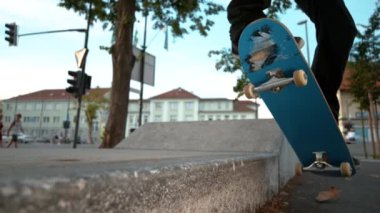 Slow Motion Close Dof: Genç erkek kaykaycı kuyruğu şehir kaykay parkında beton bir çıkıntıyı öğütüyor. Tanımlanamayan kaykaycı adam şehrin güzel bir sonbahar gününde kaykayıyla güzel numaralar yapıyor..