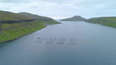 Hava: pitoresk Faroe Adaları'uzak kıyı kenti yakınlarında büyük bir balık çiftliği yukarıda uçan. Doğal yeşil dağların küçük sakin İskandinav balıkçı köyü kuşatır. Güzel engebeli doğa.