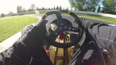 Güneşli bir günde asfalt pisti boyunca hız yapan bir go-cart sürüyorum. Siyah takımlı hızlı bir arabayı engebeli bir yarış pistinin keskin virajlarında sürmek. Parlak güneş yarışçıların üzerinde parlıyor