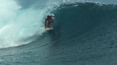 Slow Motion, Close Up: Vahşi okyanus dalgaları Tahiti 'de yazın tadını çıkaran profesyonel sörfçünün üzerine kıvrılıyor. Büyük bir fıçı dalgasında sörf yapan sporcunun muhteşem manzarası güzel sahil kıyısında sıçrıyor..