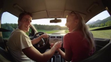 Slow Motion, Close Up, Lens Flare: Mutlu genç kadın ve erkek, güzel bir yaz akşamında kırsal alanda gezinti yaparken arabalarında dans ediyorlar. Neşeli beyaz çift eğleniyor..