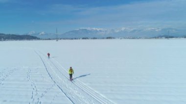 Hava: Güneşli bir günde iki bayan turist Slovenya 'da kayak yaparken eğleniyor. İki aktif kadının kayaklarıyla engin karlı düzlüklerden geçerken çekilmiş havalı bir fotoğrafı. Eğlenceli etkinlik.
