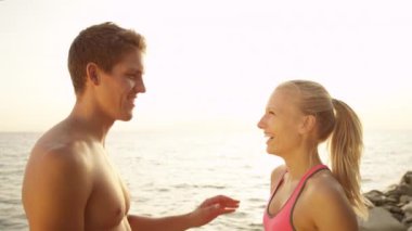 Slow Motion Close: Neşeli Kafkasyalı erkek ve kadın güneşli bir günde sakin deniz kenarında yaptıkları egzersizi kutluyorlar. Başarılı bir çalışmadan sonra neşeli bir çift beşlik çakar.