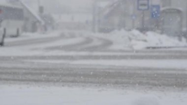 Kar fırtınası, cennet gibi bir kış gününde boş asfalt yolu kaplıyor. Küçük bir kasabanın boş sokaklarının sinematik görüntüsü. Karlı yolun kenarında boş boş duran bir otobüsle..