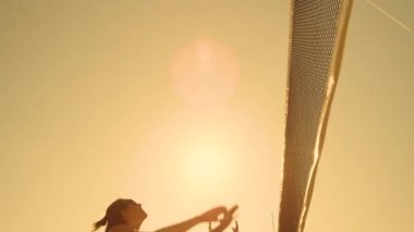 Yavaş Hareket, Düşük Açı, Close Up, Sun Flare: Plaj voleybolu oynayan atletik kız havada atlar ve güzel bir yaz akşamı net üzerinden topa vurur. Beyaz kadın bir puan.
