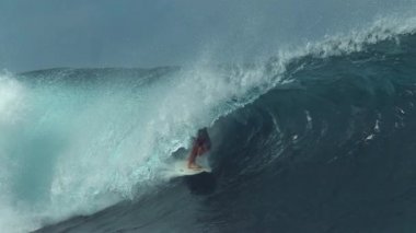 Genç sörfçü, büyük bir zümrüt dalgasında sörf yaparak muhteşem yazın tadını çıkarıyor. Formda erkek turist, Tahiti sahillerine doğru koşan büyük bir fıçı dalgası yakalıyor. Aşırı su sporu.
