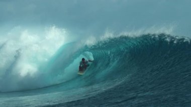 Slow Motion, Close Up: Pro sörfçü büyük bir tüp sürüyor ve elini muhteşem kristal berrak okyanus suyunda sürüklüyor. Sporcu tatilde. Tahiti 'de muhteşem çay kakası içinde sörf yapıyor..