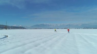 Gök olayları: iki aktif kadın turistler uçan cross country kayak güneşli bir günde Slovenya pitoresk kırsal kesimde. İki kadın arasında büyük bir karlı düz ile güzel bir dağ kayak