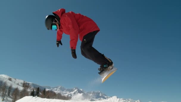 スローモーション閉じる 極端なスノーボーダーは大きな山のスキーリゾートにジャンプします 圧雪のスノーパークではキッカーを脱着するスノーボードの詳細 スヌブパークでの晴れた冬の日にスノーボードジャンプ — ストック動画