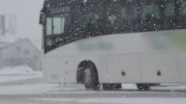 慢动作 在一个下雪天 白色的公共汽车在一个巴士站减速 恶劣的天气笼罩着城市的街道 覆盖着积雪 旅游车因天气恶劣而停站 — 图库视频影像