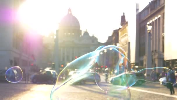 慢动作 特写镜头 镜头闪烁着 多彩的肥皂泡在太阳光照射的梵蒂冈广场周围飞舞 在历史性的圣彼得大教堂和气泡上闪烁着金光闪闪的晨光 — 图库视频影像
