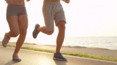 Slow Motion, Low Angle, Lens Flare: Güzel bir yaz gününde sahilde koşan tanınmayan genç adam ve kadın fiziksel olarak iyi durumdalar. Uygun çift eğitiminin sinematik çekimi.