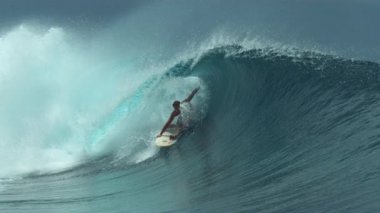Slow Motion, Close Up: Muhteşem erkek sörfçü güneşli Tahiti 'de sörf yapmak için mükemmel bir günde zümrüt varil dalgası sürüyor. Genç sörfçü Fransız Polinezyası 'nda mükemmel dalgaları yakalamanın keyfini çıkarıyor..