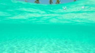 Slow Motion, Sualtı: Zümrüt renkli denizin göz kamaştırıcı manzarası ve nefes kesici güneşli Maldivler 'de boş kumlu deniz yatağı. Camsı su, kameranın merceğine sıçrayıp turkuaz okyanusu çekiyor..