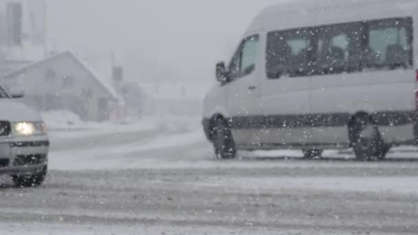 スローモーション Dof 激しい吹雪の中 白いバンは脇道に入ります 牧歌的な冬の天気は都市交通のためのアスファルト道路を危険にします 汚れた雪の中でヴァンが痕跡を残す — ストック動画