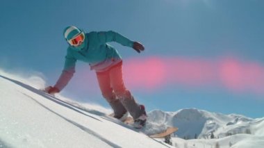 Slow Motion Kapanış. Güneşli kış gününde dağlarda snowboard yapan gülümseyen kız. Kameranın önünden toz kar süren serbest kayakçı taze kar yüzeyinde el sürüyordu. Kadın taşra kayağı