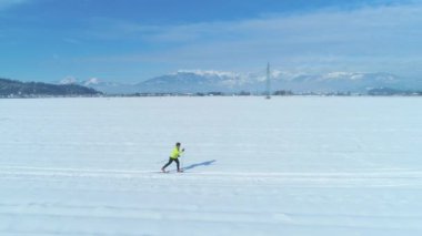Slovenya 'da geniş bir karlı ovada kayak yapan aktif bir kadın ile uçmak. Resimli kış manzarası, güneşli günün tadını çıkaran kadın kayakçıyı çevrelemektedir. Eğlenceli kış aktivitesi