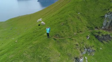 Kallur deniz fenerinde yürüyüş yapan kadın fotoğrafçı çimenli bir dağdan nefes kesen okyanusun fotoğraflarını çekiyor. Genç bayan turistleri gezdirip manzaralı kırsal bölgeleri fotoğraflıyorum..