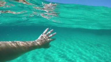 Slow Motion, Half Sualtı, Pov: Güneşli adadan çok uzakta, turkuaz bir okyanusta yüzmek. Akdeniz 'de dalarken kolunu uzatan bir adamın sinematik ilk insan görüntüsü