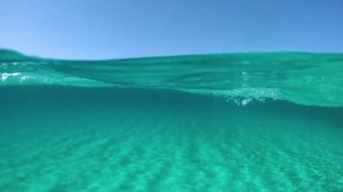 Slow Motion, Half Underwater, Pov: Turkuaz denizde yüzen aktif erkek turist uzak adaya doğru gidiyor. Güneşli Sardunya 'da yaz tatili boyunca yüzen erkeklerin sinematik manzarası.
