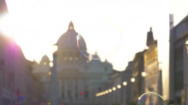 Vatikan, Eylül Slow Motion, Close Up, Lens Flare, Dof: Havalı sokak sanatçıları büyük sabun köpükleri yaparken çocuklar arkalarından koşup onları patlatıyor. Gün batımında yüzen renkli kabarcıklar