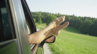 Slow Motion, Close Up: Tanınmayan genç bir kadın güneşli bir günde araba sürerken çıplak ayaklarını arabanın camından dışarı çıkarıyor. Kız parmaklarını havada oynatıyor..