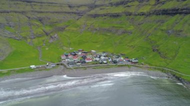 Anteni: boş bir siyah plaj hemen yanında küçük bir kıyı kenti uzak uçan. Küçük okyanus dalgalarının Faroe Adaları'nda büyük bir çimenli Fiyordu kıyısında ulaşmak. Sarp yeşil tepeler çevreleyen küçük köyü.