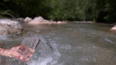 Slow Motion, Close Up: Bilinmeyen kişi güneşli bir yaz gününde sakin bir kaynaktan kristal berrak su topluyor. Tanımlanamayan bir kızın sakin bir dereden ferahlatıcı su çekerken çekilmiş sinematik görüntüleri..