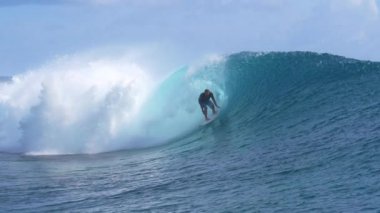 Slow Motion, Close Up: Genç profesyonel sörfçü Tahiti 'de popüler bir sörf merkezinin yakınında nefes kesici bir fıçı dalgası sürüyor. Muhteşem bir sporcu yaz tatilinde okyanus dalgalarında sörf yapıyor..