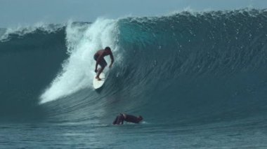 Slow Motion, Close Up: Sörfçü arkadaşı büyük fıçı dalgasında sörf yaparken zümrüt okyanusuna ördek dalışı yapıyor. İki sporcu tatilde sörf yaparken Tahiti 'de, Fransız Polinezyası' nda eğleniyor..