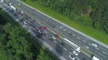Yaz tatili sezonu ve yoğun saatlerde beton otoyol boyunca yavaşça ilerleyen bir trafik sıkışıklığının üzerinde uçmak. Arabalar ve kamyonlar trafiğin yanından geçerek ters yönde ilerliyor..