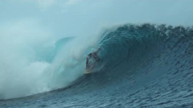Slow Motion, Close Up: Aktif yaz tatilindeki kaygısız genç adam nefes kesici bir fıçı dalgasında sörf yapıyor. Güzel bir okyanus dalgası erkek sörfçüyü Teahupoo, Tahiti 'nin güneşli sahillerine doğru itiyor.
