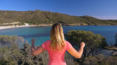 Slow Motion, Close Up: Bilinmeyen kadın çarpıcı mavi koyu izlerken kollarını uzatıyor. İtalyan sahili üzerinde muzaffer kadın turistin sinematik görüntüleri..