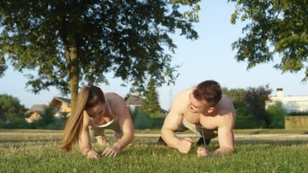 慢动作 在公园里工作的一对快乐的夫妇在侧身时拿着一块木板 运动的白人男友和女友在外面训练 享受夏天 — 图库视频影像