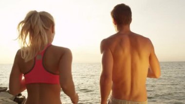 Slow Motion, Close Up, Lens Flare: Bilinmeyen adam ve kadın başarılı bir koşudan sonra kollarını uzatıyorlar. Kıyı şeridine doğru koşan ve kutlama yapan antrenman arkadaşlarının sinematik çekimi..