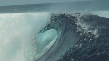 Slow Motion, Close Up: Güneşli Pasifik 'teki egzotik bir adanın kıyısına doğru büyük bir su sıçrayan fıçı dalgası hücum eder. Su damlacıkları yaz güneşinde parlıyor Büyük tüp dalgaları çılgınca çarpıyor.