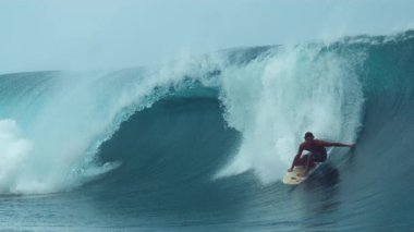 Slow Motion, Close Up: Neşeli genç sörfçü elini güzel Fransız Polinezyası 'nda sürdüğü varil dalgası boyunca sürüklüyor. Destansı okyanus dalgalarında sörf yaparak harika bir yaz gününün tadını çıkaran adam..