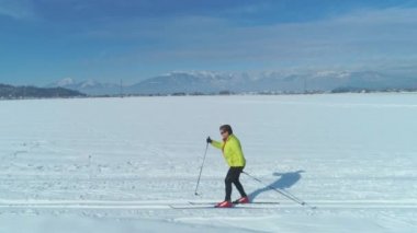 Hava: Etkin kadın, Slovenya 'nın manzaralı kırsalında kayak yaparak kışın tadını çıkarıyor. Enerjik bayan turist güneşli bir günde karlı bir ovada kayak yaparken eğleniyor..